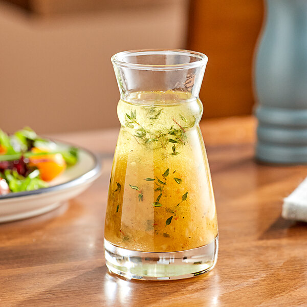 An Arcoroc glass carafe filled with liquid on a table.