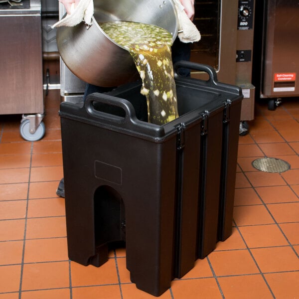 A man pouring liquid into a Cambro insulated soup carrier.