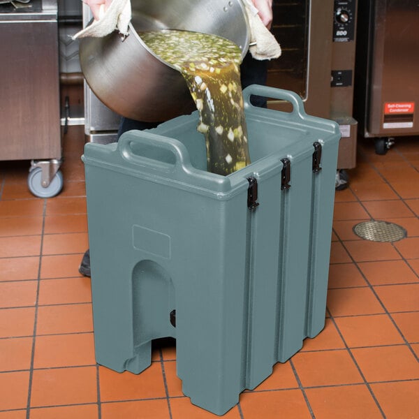 A man pouring liquid into a Cambro insulated soup carrier.