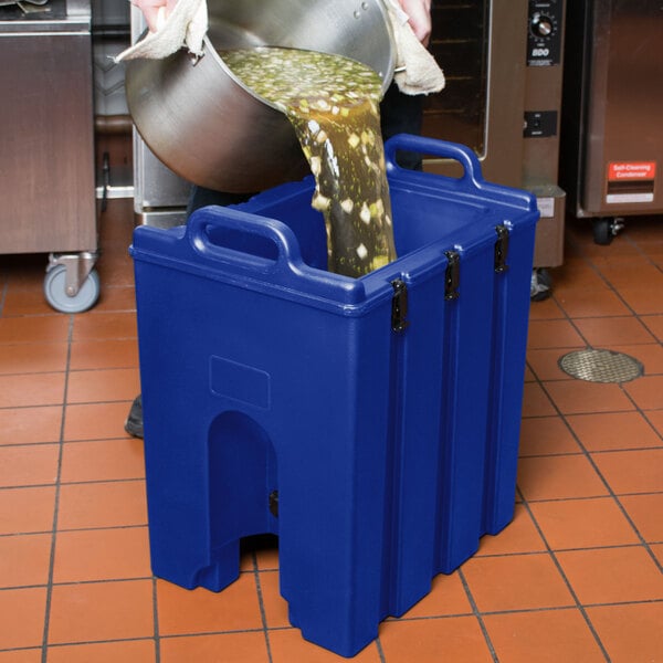 A person pouring liquid into a Cambro navy blue insulated soup carrier.