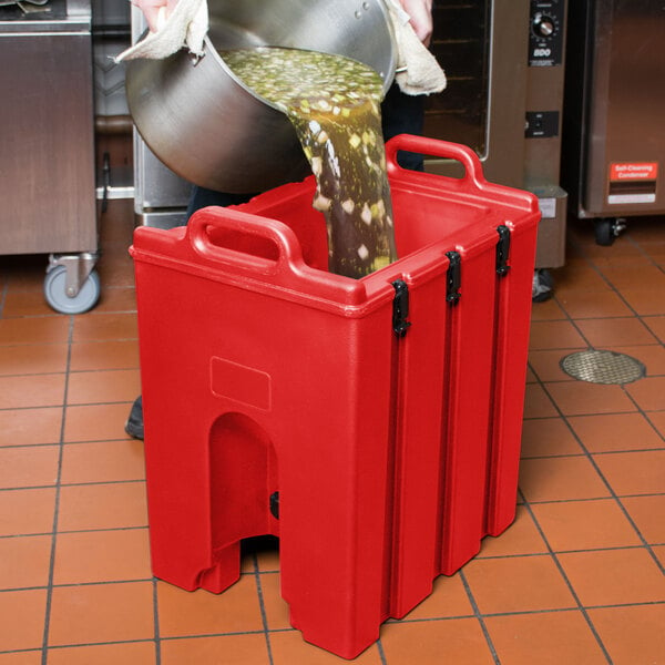 A person pouring liquid into a red Cambro soup container.