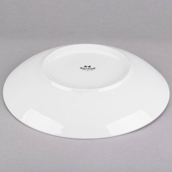 A Tuxton bright white china pasta bowl with an embossed rim on a gray surface.