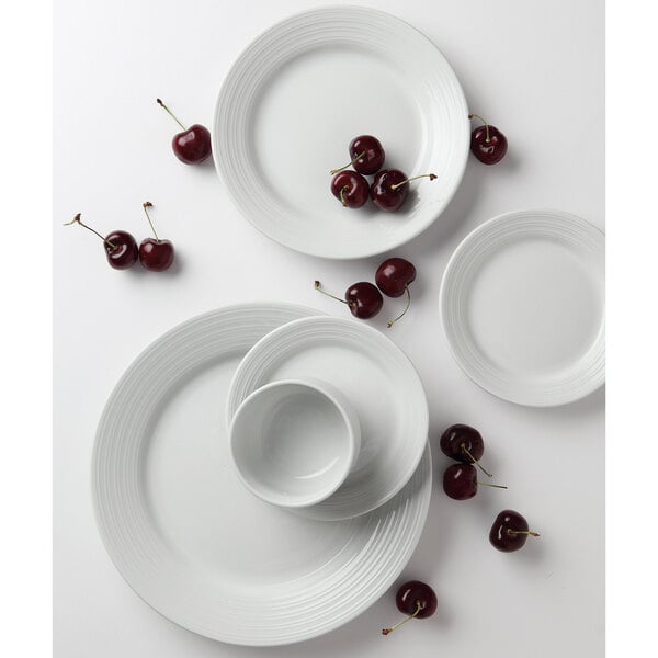 A close-up of a Tuxton bright white embossed china plate with cherries on it.