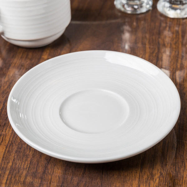 A Tuxton Pacifica saucer with an embossed rim on a table.