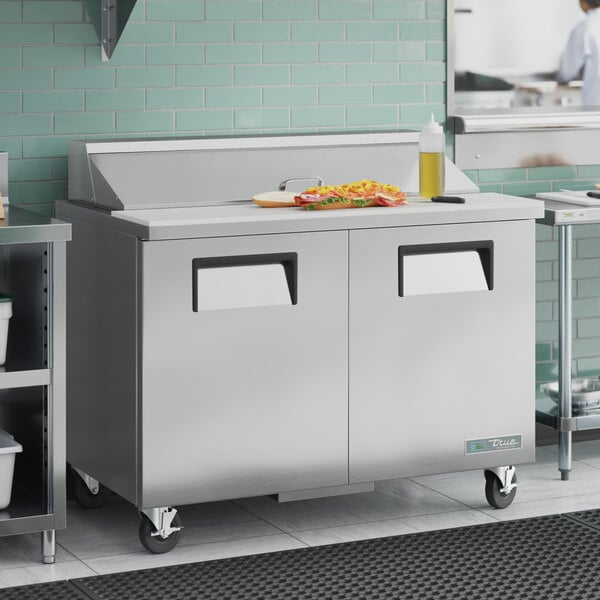 A True 2 door refrigerated sandwich prep table with a stainless steel counter top.
