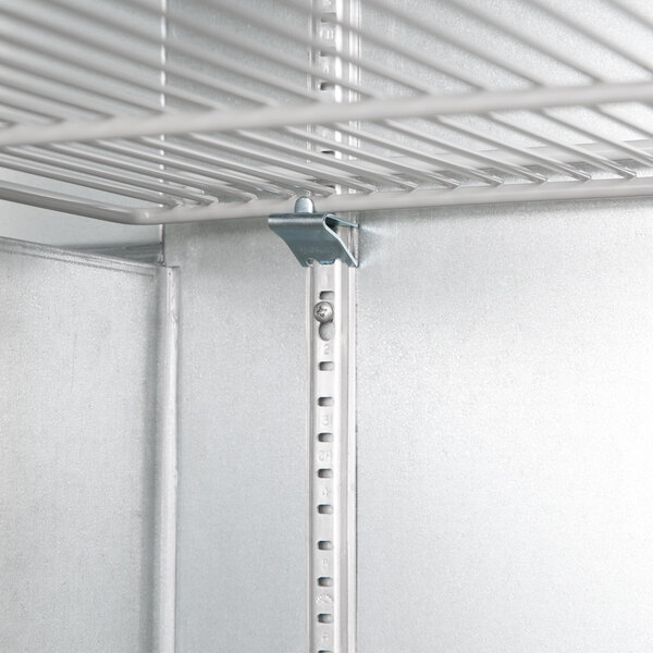 A metal shelf with a metal clip inside a Beverage-Air back bar refrigerator.