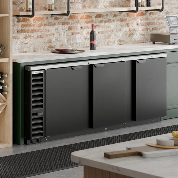 A black, counter-height, three-door back bar refrigerator designed for commercial use.