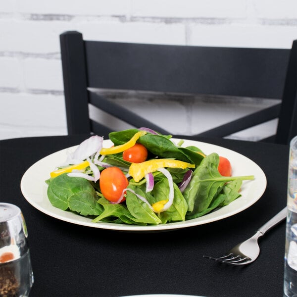 A 10 Strawberry Street porcelain luncheon plate with a salad of spinach, tomatoes, and onions.