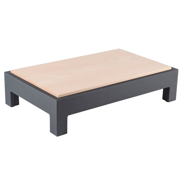 A Vollrath Cubic display cutting board table on a wooden table with a black base.