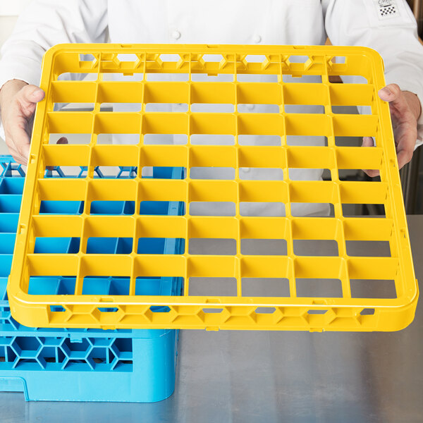 A person holding a yellow Carlisle plastic tray with 49 compartments.