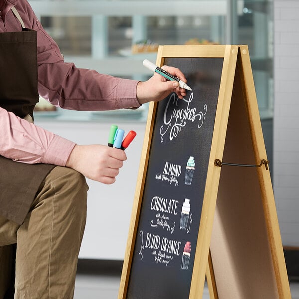 A person writing on a Choice A-Frame Marker Board sign.