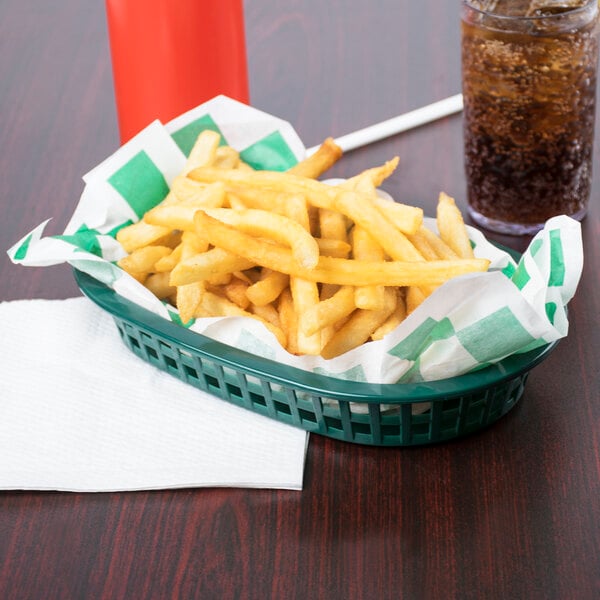 A Tablecraft oval forest green plastic fast food basket filled with french fries and a drink on a table.