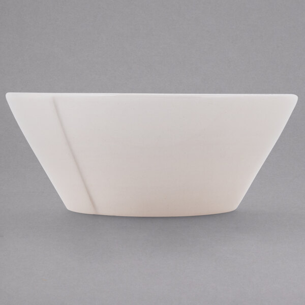 A close-up of a Libbey Farmhouse ivory serving bowl with a curved edge.