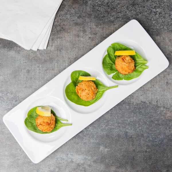 A Libbey porcelain 3-well tray with three small plates of food on a table.
