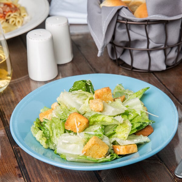 A round blue and white porcelain bowl filled with salad on a table.