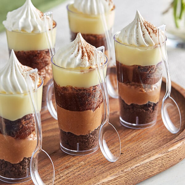 A glass cup with a layer of chocolate and whipped cream using a Visions clear plastic spoon.