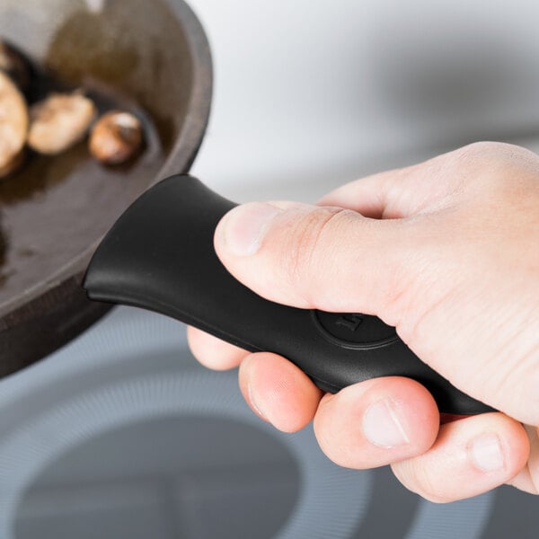 A hand holding a black Lodge handle over a pan of food.