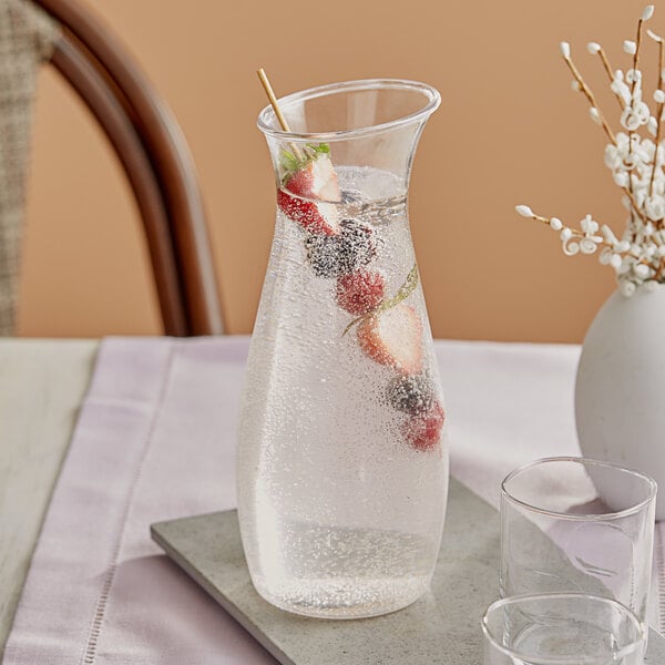 A Carlisle clear plastic carafe with a drink and fruit in it on a table.
