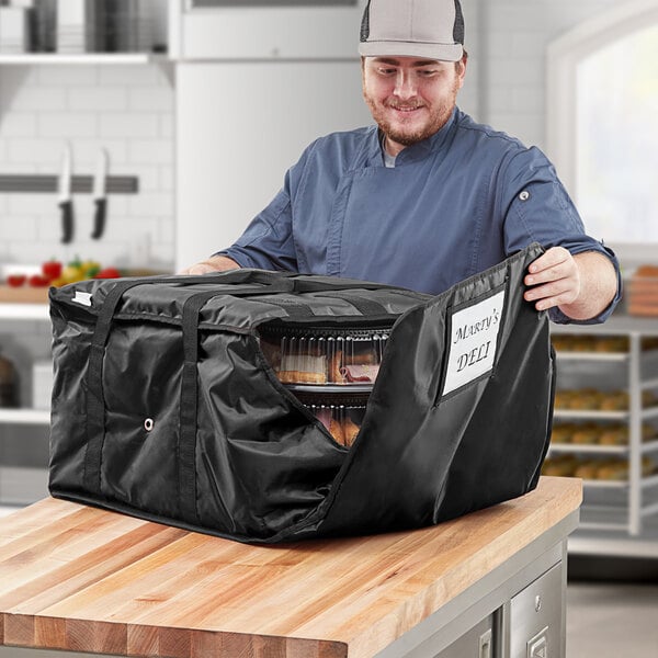 A man in a kitchen with a CaterGator Dash insulated deli tray and party platter bag.