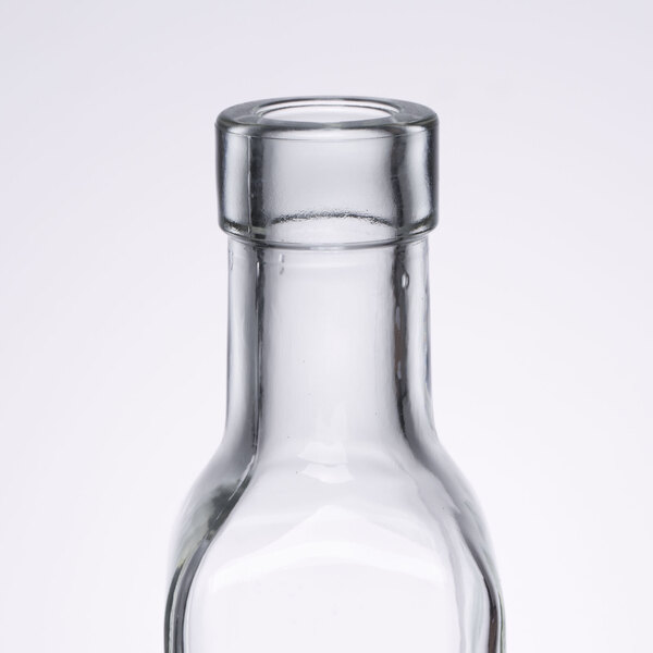 A close-up of a Tablecraft clear glass olive oil cruet with a pourer stopper.