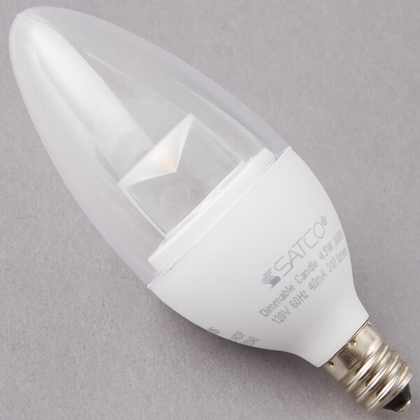 A Satco clear LED light bulb with a candelabra base on a gray surface.