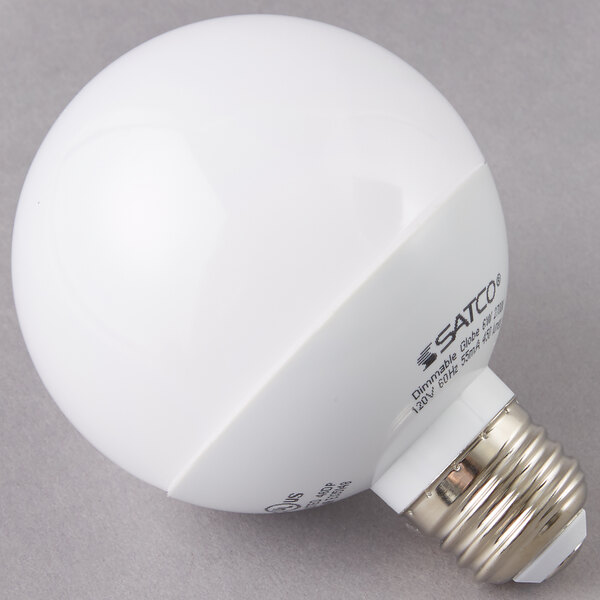 A Satco frosted warm white LED globe light bulb on a gray surface.