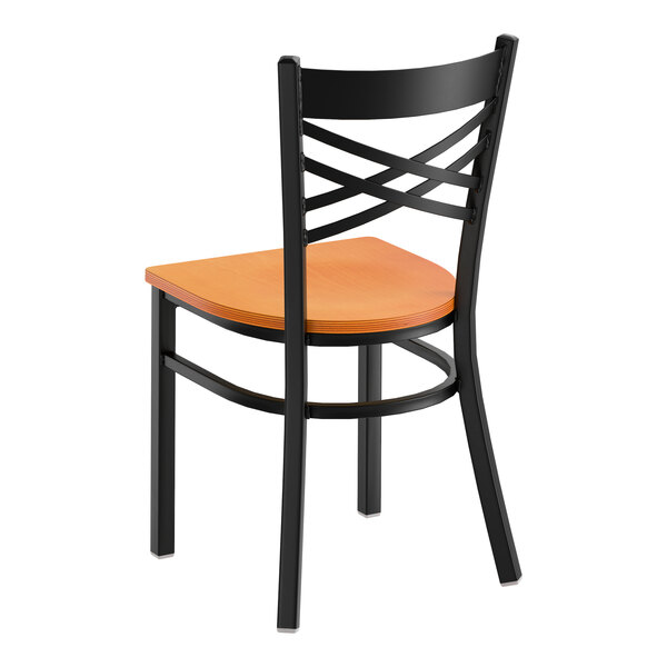 A black metal cross back chair with a cherry wood seat.