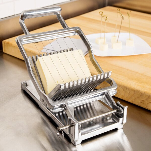 A piece of cheese being sliced in a Nemco Easy Cheeser.
