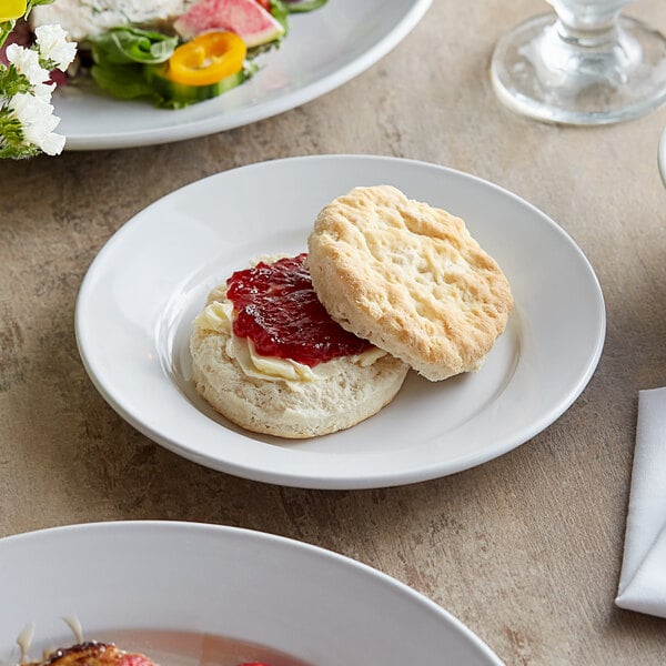 A white Acopa stoneware plate with a biscuit and jam on it.