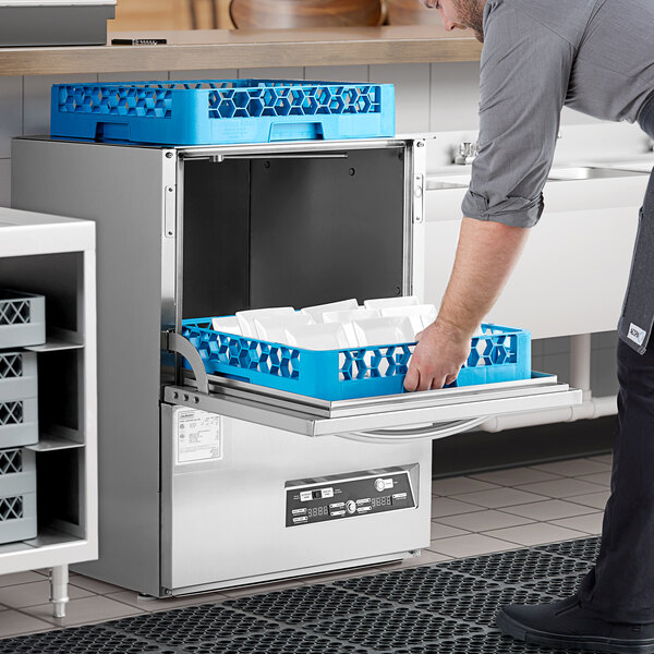 A man opening the door of a Jackson DishStar undercounter dishwasher with a blue tray.