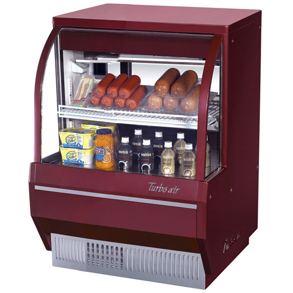 A red Turbo Air refrigerated deli case displaying sausages and other food.