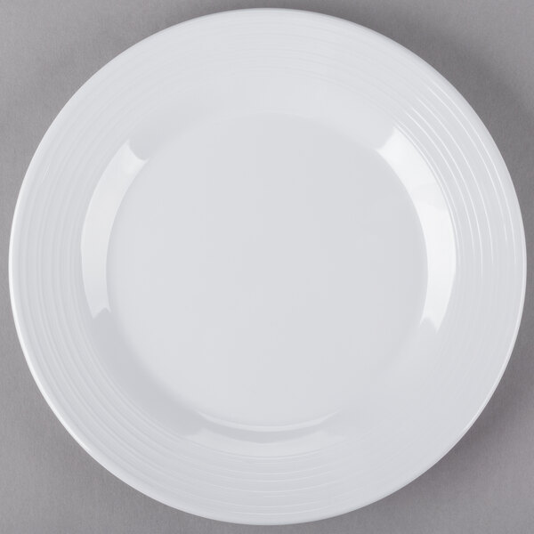 A white Minski melamine plate with a textured rim on a gray surface.