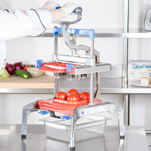 A person using a Prince Castle Saber King Tomato Slicer to slice tomatoes.