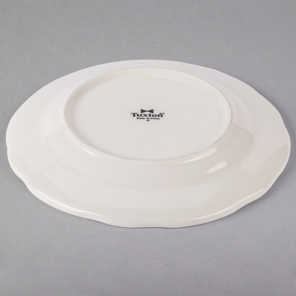 A Tuxton ivory china plate with a scalloped edge.