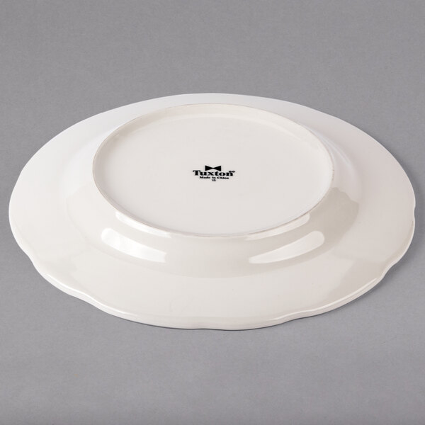 A Tuxton ivory china plate with a scalloped edge.