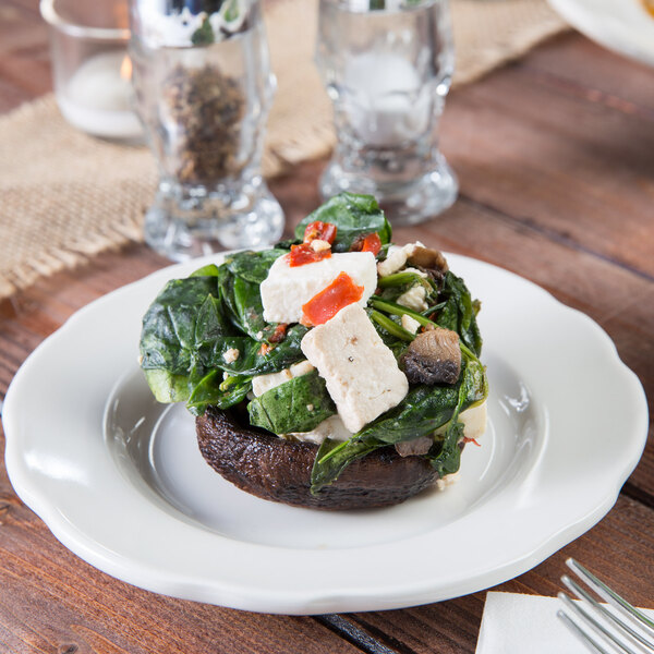 A Tuxton Shell china plate with a mushroom and spinach dish on it.