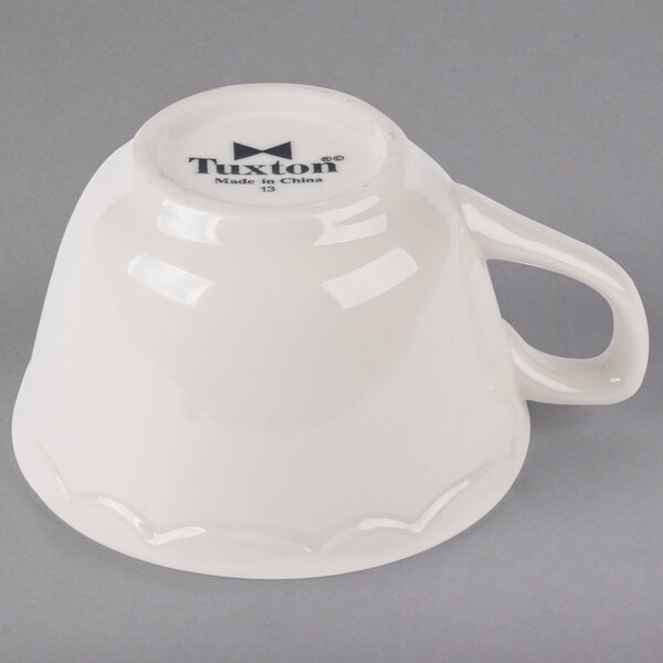 A white china cup with a handle.