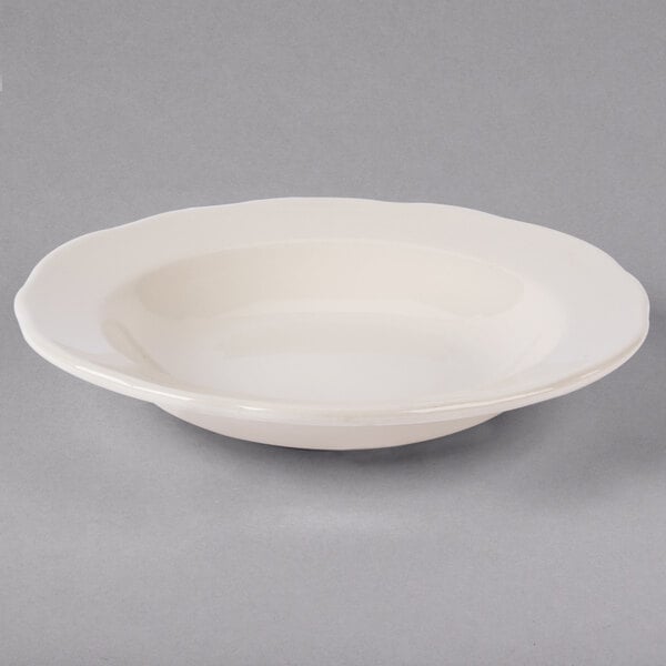 A white Tuxton china bowl with a scalloped edge.
