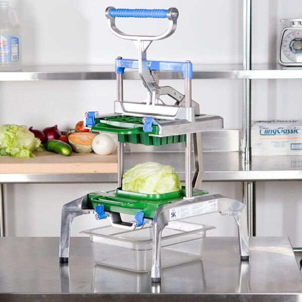 A Prince Castle Saber King lettuce chopper on a table with lettuce in it.
