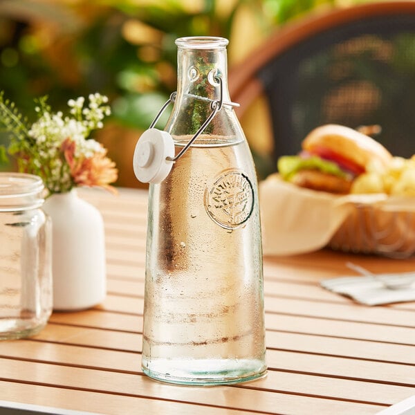 A Tablecraft green tint glass carafe with water on a table.