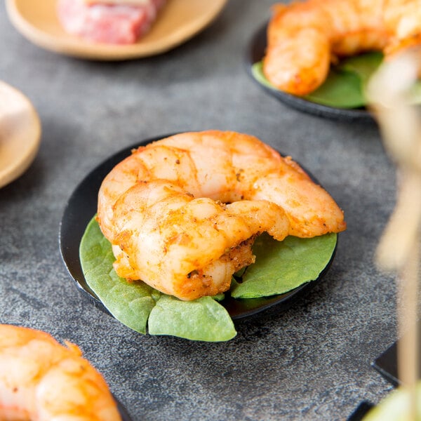 A Tablecraft black bamboo round dish holding shrimp on a table.