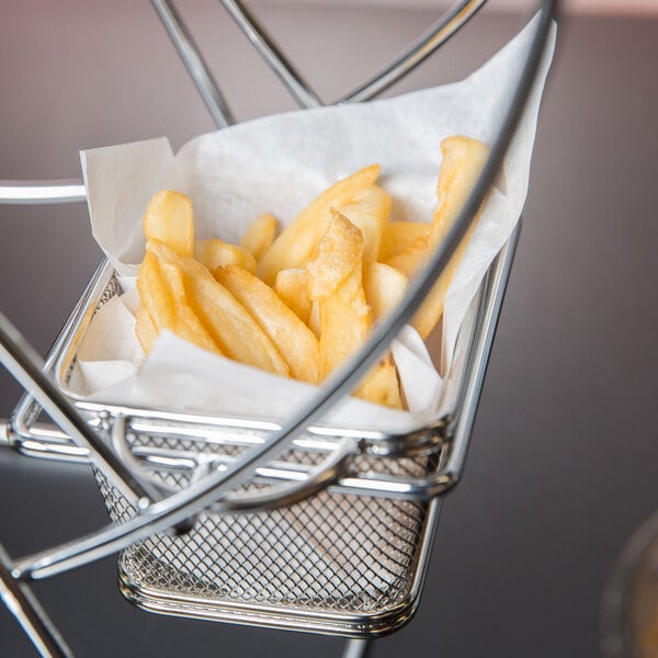 A Clipper Mill chrome ferris wheel rack with 5 baskets filled with french fries on a table.