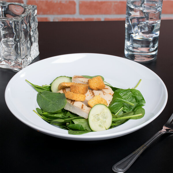 A white melamine bowl filled with salad, chicken, and vegetables.