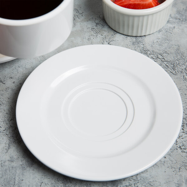 A white Elite Global Solutions double well coffee saucer holding a cup of coffee.