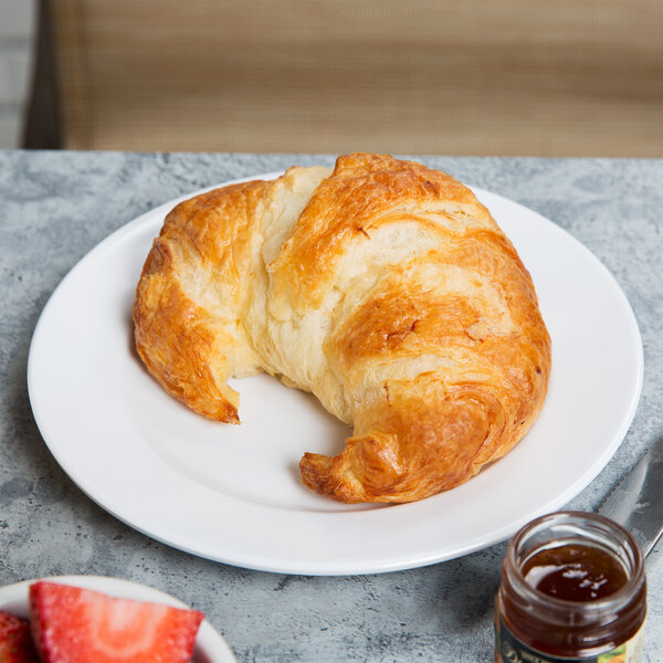 A croissant and a jar of jam on an Elite Global Solutions white melamine platter on a table.