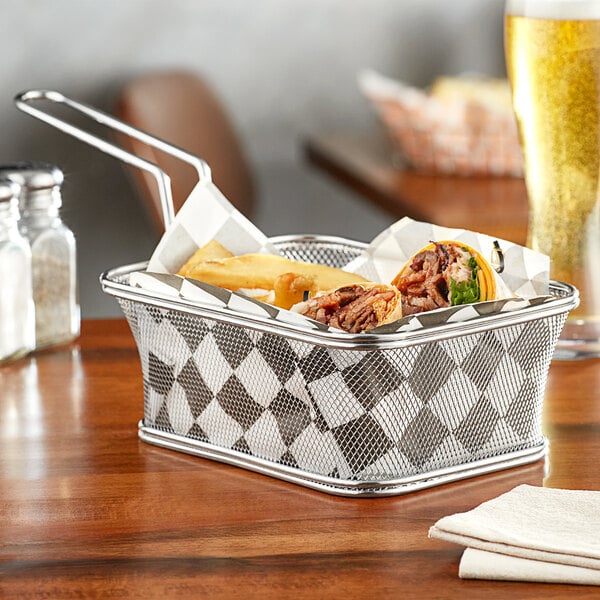 A Clipper Mill stainless steel serving fry basket filled with food on a table.