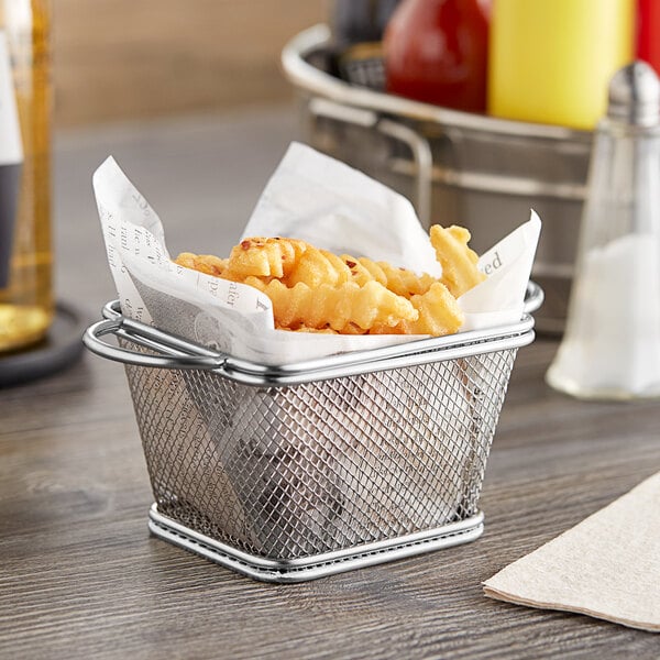 A Clipper Mill stainless steel single serving fry basket filled with french fries on a table.