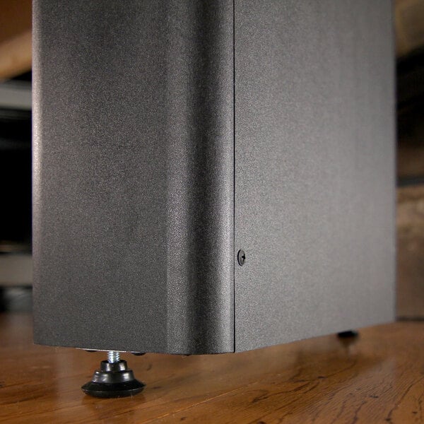 A close up of the black rectangular object with a black rubber pad on a wooden floor.