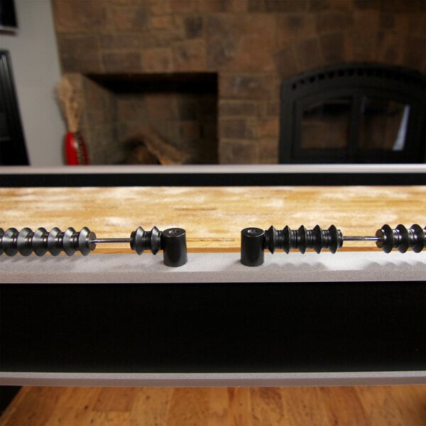 A black and silver Atomic shuffleboard table with black and white objects on it.
