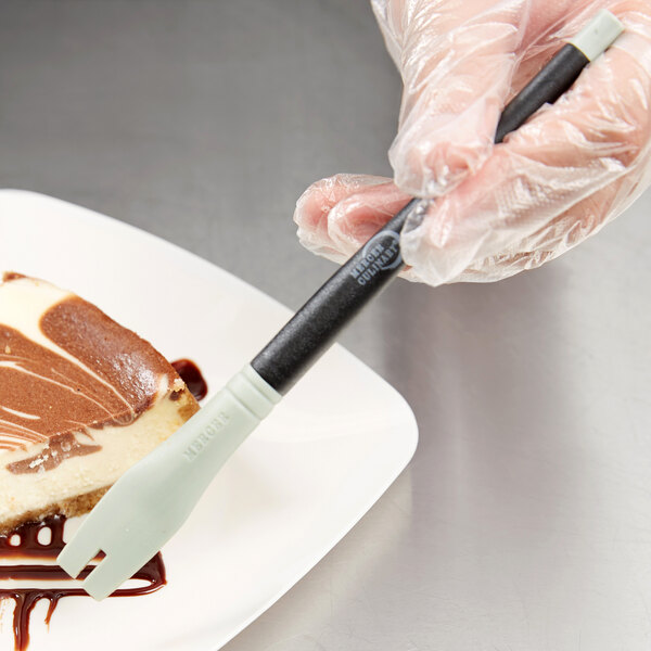 A person using a Mercer Culinary silicone plating tool to plate a piece of cake.